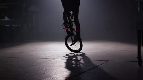 Extreme bmx rider performs dangerous tricks in dark urban warehouse on red epic