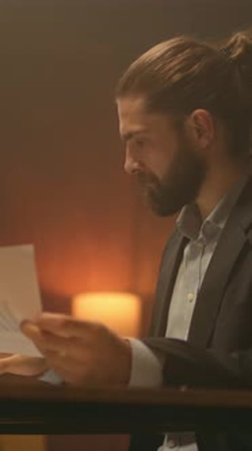 Pensive Man Reviewing Documents at Desk in Office
