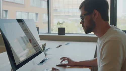 Young Adult Analyzes Data at Office Desk