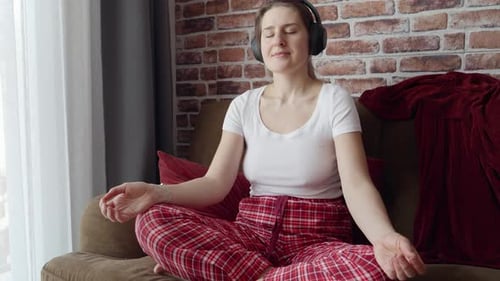 Woman Meditating with Headphones on Sofa