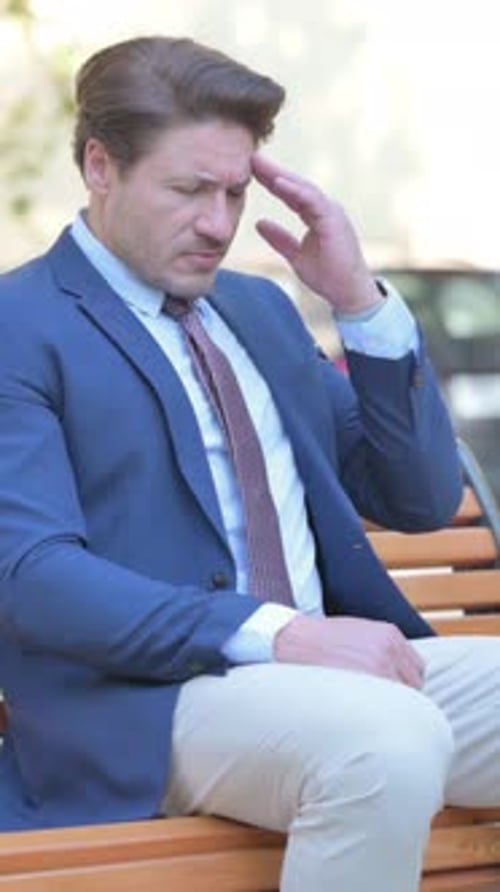 Man In Suit Sits On Bench Thinking Deeply