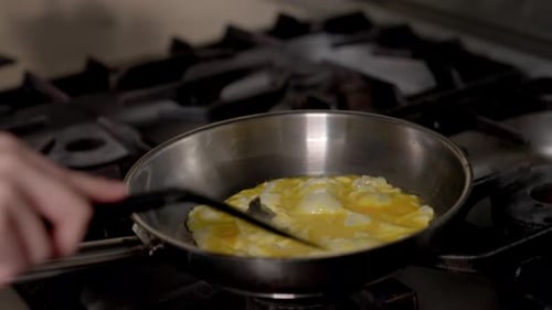 Cooking Scrambled Eggs in Frying Pan on Gas Stove Close Up
