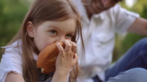 Child Eats Pastry With Adult in the Background
