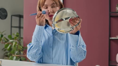 Woman Applying Makeup with Brush and Mirror