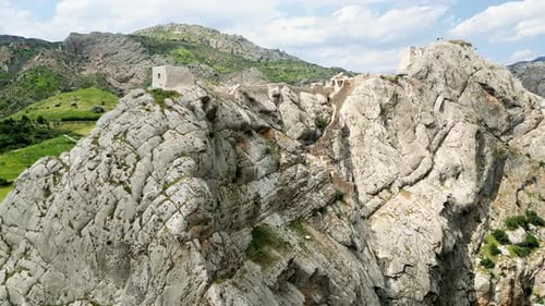 Aerial drone view of a historic fortress built along dramatic mountain cliffs overlooking a canyon v