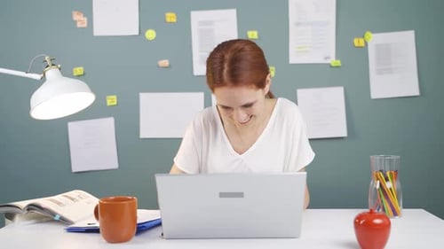 Woman Working At Desk On Laptop Laughing