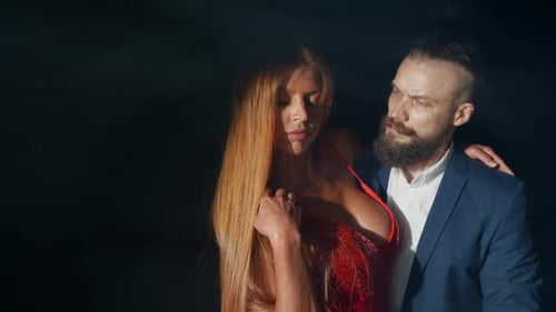 Elegant Woman and Man Posing in Dark Setting