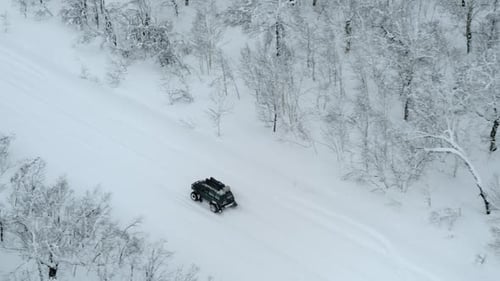 Off road vehicle with track tires driving snowy forest road