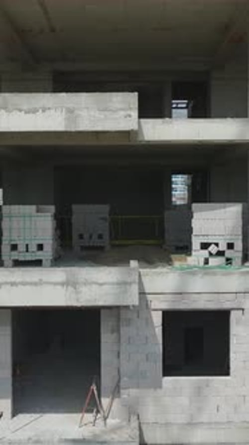 Vertical Drone Shot of Workers Assembling Walls Inside Unfinished Apartment Building