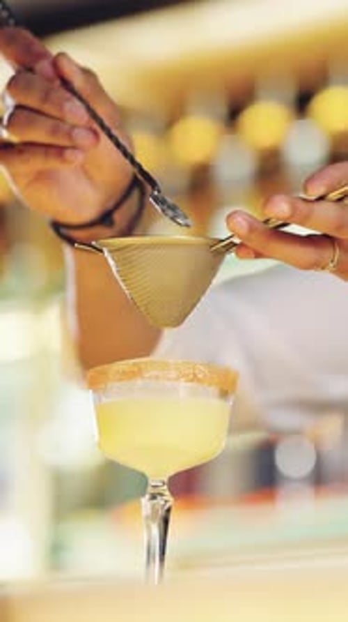 Bartender Straining Cocktail into Glass with Sugared Rim