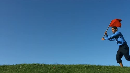 Man Runs Barefoot With Red Flag Uphill Outdoors