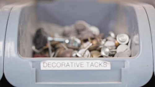 Extreme rack focus to label reading 'decorative tacks' on bin of metal tacks