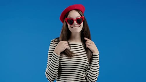 Playful Stylish Woman Smiling Flirting to Camera on Blue Studio Background