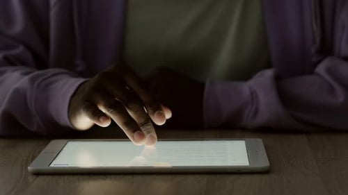 Hand auf digitaler Tablet-Tastatur, Nahaufnahme eines afroamerikanischen Mannes, der im Büro arbeitet, aus der Ferne tippt