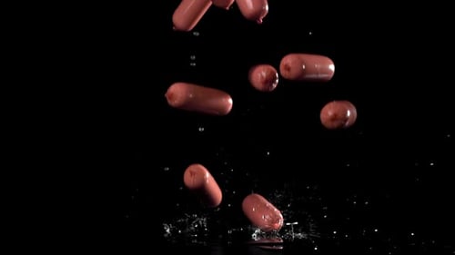 Sausages Fall in Water on a Black Surface
