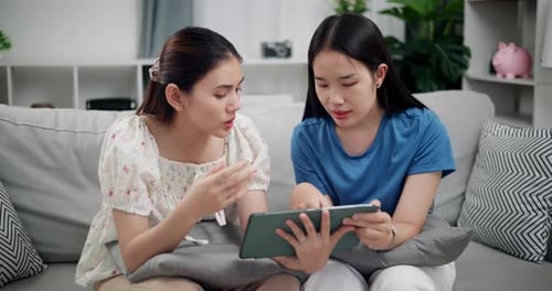 Two Friends Using Tablet Together on Sofa