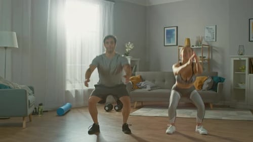 Muscular Athletic Man and Beautiful Fitness Woman in Workout Clothes are Doing Squat Exercises in T