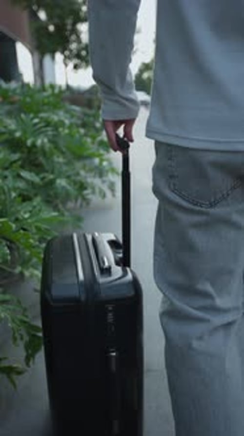 Traveler Walking and Pulling Suitcase Down City Street