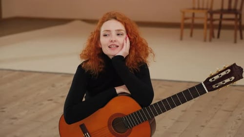 Young Woman with Guitar Smiling and Posing Indoors