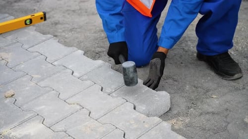 Construction Worker Installing Paving Stones with Rubber Mallet