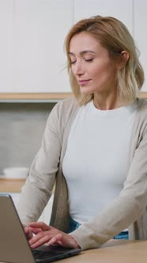 Woman Using Laptop in Bright Kitchen During Daytime