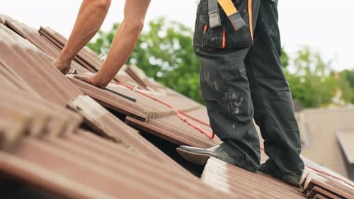 Handyman fixing roof with new tiles, work in hight
