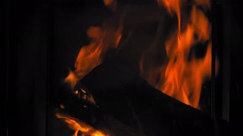 Burning Flame At Fireplace on wooden logs. Close up shot of a yule log burning in a fireplace.