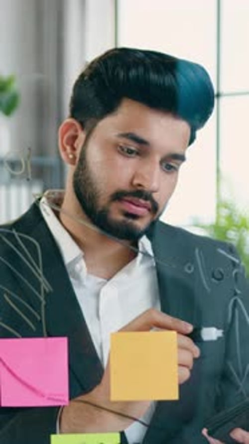 Likable Man Worker Writing Notes on Glass Board Working in Modern Office Over Busines Project and