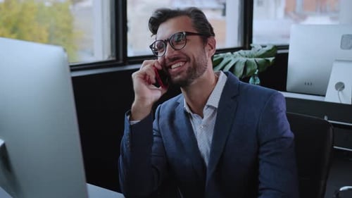 A Professionally Dressed Man Actively Engaging in a Phone Call Within a Modern Office Space
