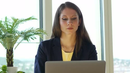 Female Business Person Working on Laptop Computer Desk in City Office