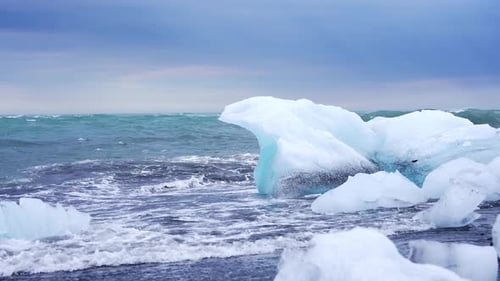 Des vagues s'écrasent contre des icebergs sur le littoral islandais de Diamond Beach