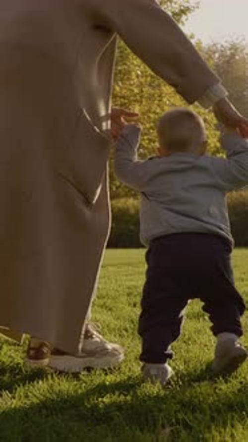Vertical video Baby enjoys reading a book on a sunny evening in the park