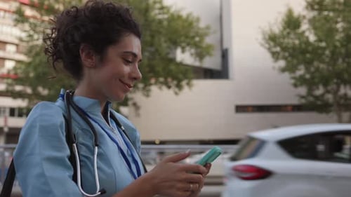 Nurse Smiling While Using Smartphone Outdoors
