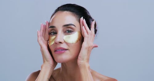 Woman Applying Gold Eye Masks for Skin Care
