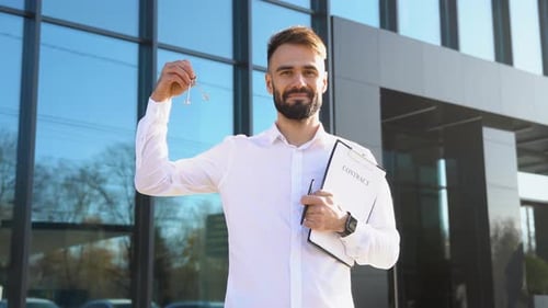 Realtor Agent with Keys and Documents in Hand Against the Background of Modern House