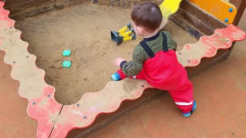 Toddler baby is playing in the sandbox on the playground. A child plays in the sand. Kid boy aged tw