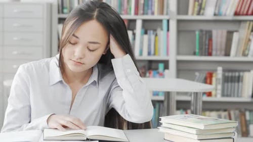 Exhausted Asian Young Woman Dozing Off While Studying in the Library