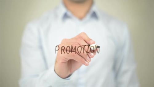 Hand Writes Word Promotion on Clear Surface