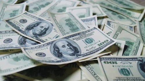 Fallende Hundert-Dollar-Scheine landen auf einem Geldstapel