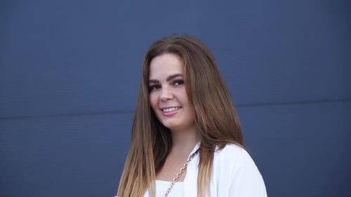 Portrait of young Caucasian girl in white shirt posing for camera. Close-up.