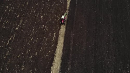 Red tractor plowing the field in Ukraine