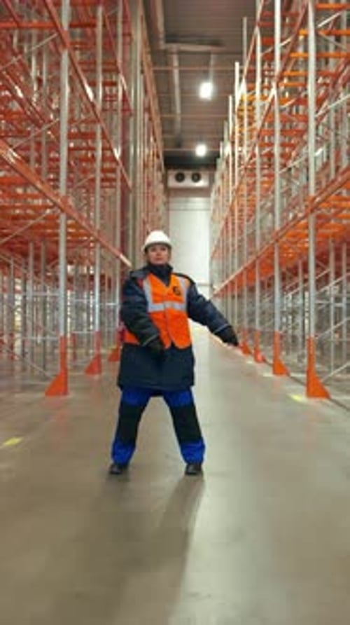 Vertical of Female Engineer Dances on Aisle Between Empty Metal Racks