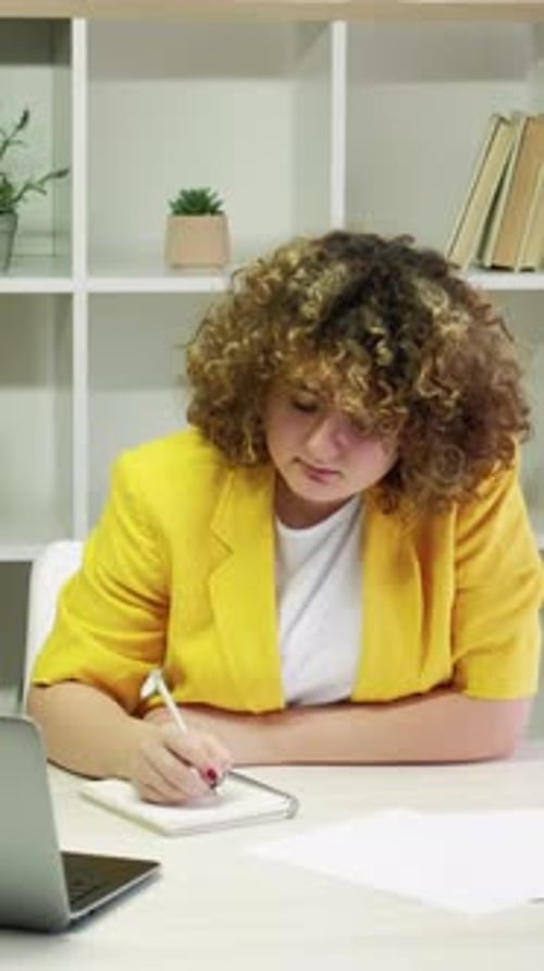 Woman With Curly Hair Writes in Notepad