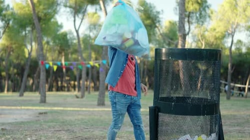 Hombre arrojando una bolsa de basura en un parque