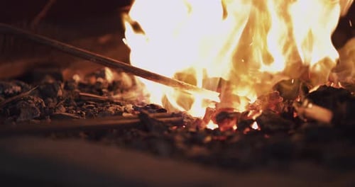 A metal rod being heated in burning fire in a welding workshop
