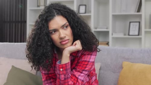Young Woman Sitting Thoughtfully on Couch at Home