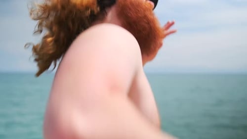 Shirtless Man Jogging Energetically on Beach Coastline