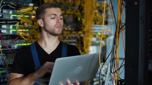 Young IT Technician Working with Laptop in Server Room
