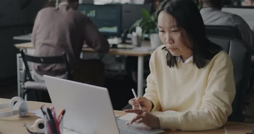 Young Woman Analyst Writing Information in Notebook and Using Laptop in Open Space Office