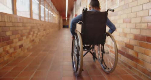 Student in wheelchair moving through school hallway with brick walls